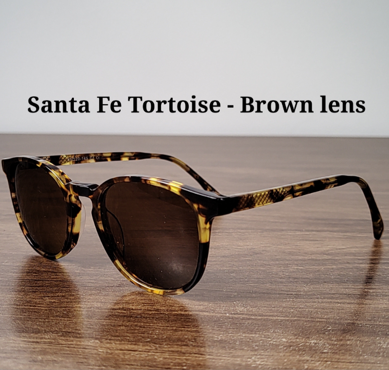 Sunglasses with tortoiseshell frame and brown lenses on a wooden surface