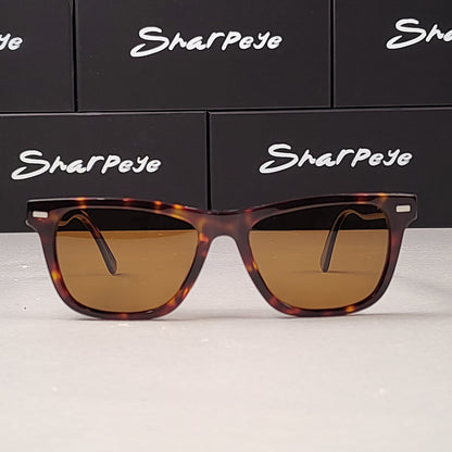 Sunglasses with tortoiseshell frame and brown lenses on a white surface with 'Sharpeye' branding in the background.