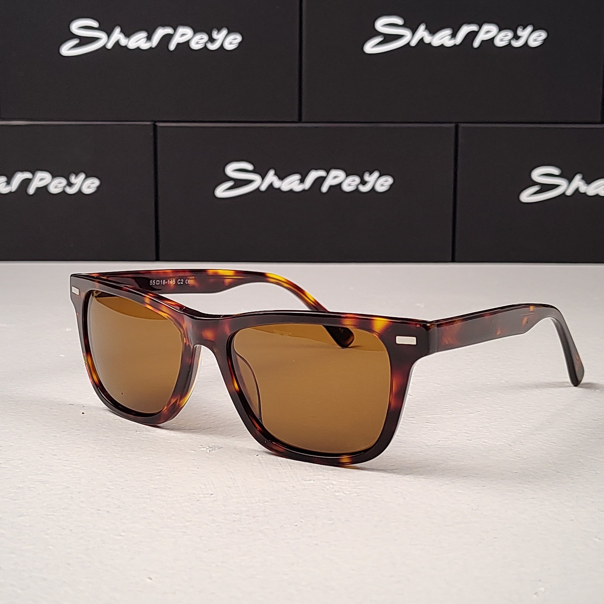 Sunglasses with tortoiseshell frame and brown lenses on a white surface with Sharpeye logo in the background.